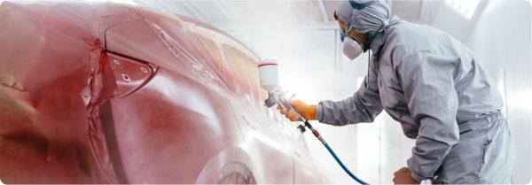 body shop technician painting red car
